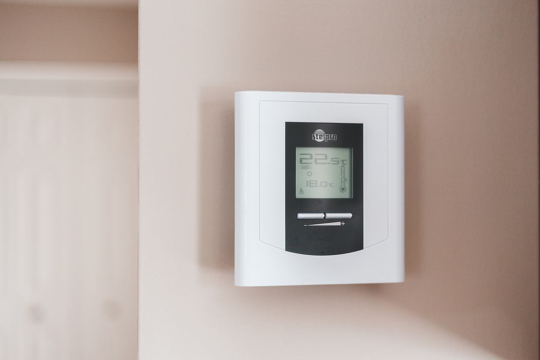 Digital thermostat on a beige wall.