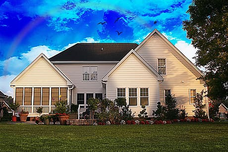 Traditional white house with a gabled roof and a screened porch at sunset.