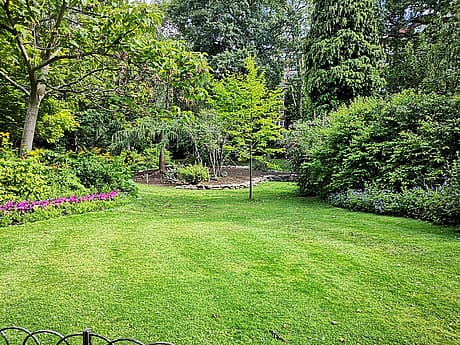 Lush green garden with manicured lawn and vibrant flower beds.