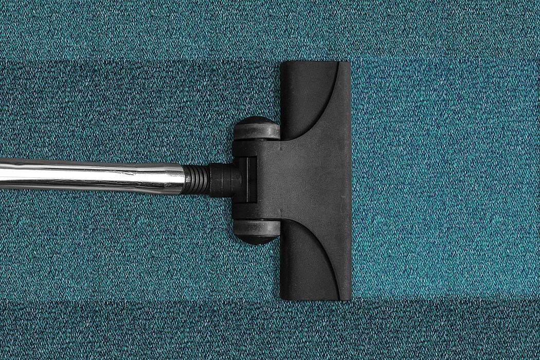 Vacuum cleaner head on a textured blue carpet.