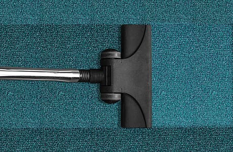 Vacuum cleaner head on a textured blue carpet.