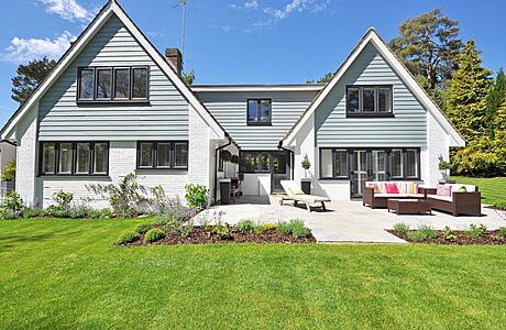 White gabled house with patio and garden.