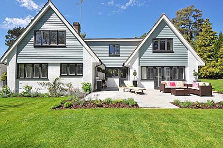 White gabled house with patio and garden.