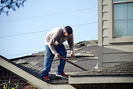 A person repairing a damaged house roof.