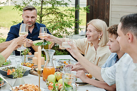 A cozy outdoor dining setup with a wooden table, flowers, and greenery as decor.