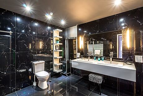 Luxurious modern bathroom with dark marble tiles, vanity, and recessed lighting.