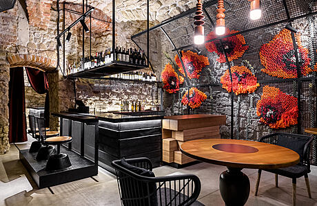 A cozy restaurant with exposed stone walls, modern lighting, and eclectic furniture.