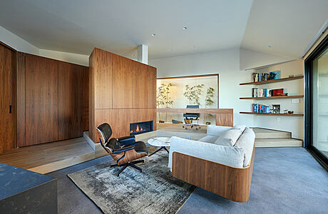 Spacious mid-century modern living room with wooden walls, floating shelves, and a fireplace.