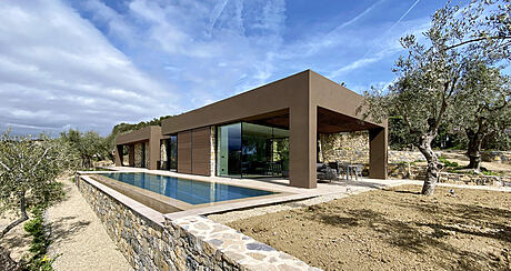 Contemporary villa with pool and large windows amidst olive trees.