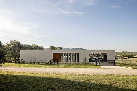 Modernist building with clean lines, wood accents, and panoramic glass windows against natural landscape.