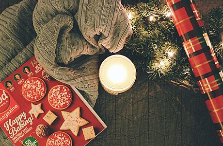 Cozy holiday setting with a magazine, candle, and Christmas lights.