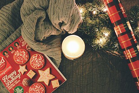 Cozy holiday setting with a magazine, candle, and Christmas lights.