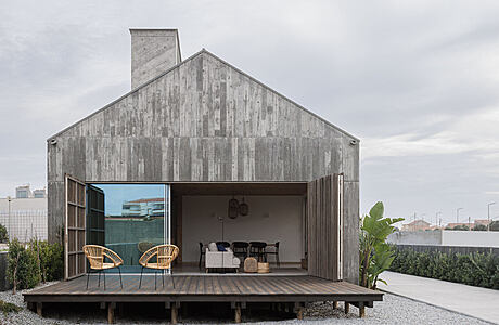 A modern rustic cabin with an open living space and a large covered patio on a wooden deck.