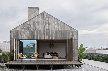 A modern rustic cabin with an open living space and a large covered patio on a wooden deck.