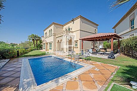Luxurious villa with a pool and garden under a clear sky.