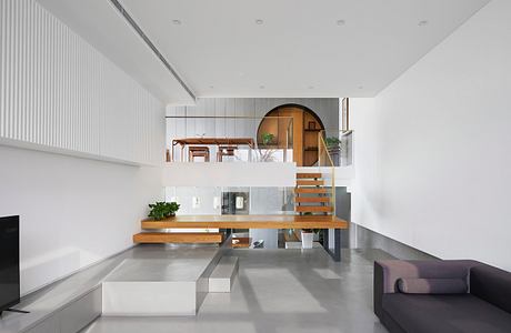 Modern minimalist living room with white walls and floating wooden staircase.