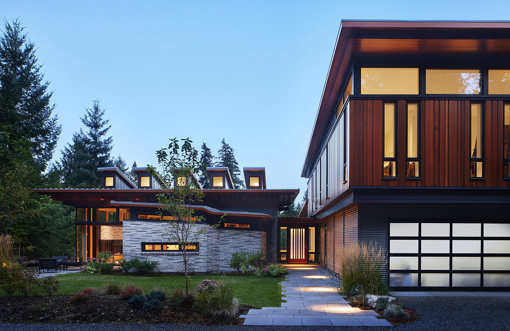 Modern home exterior at dusk with illuminated windows and landscaped garden.