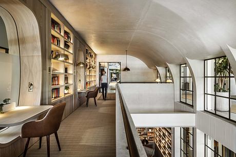 Modern library interior with curved ceiling, bookshelves, and minimalist furniture.