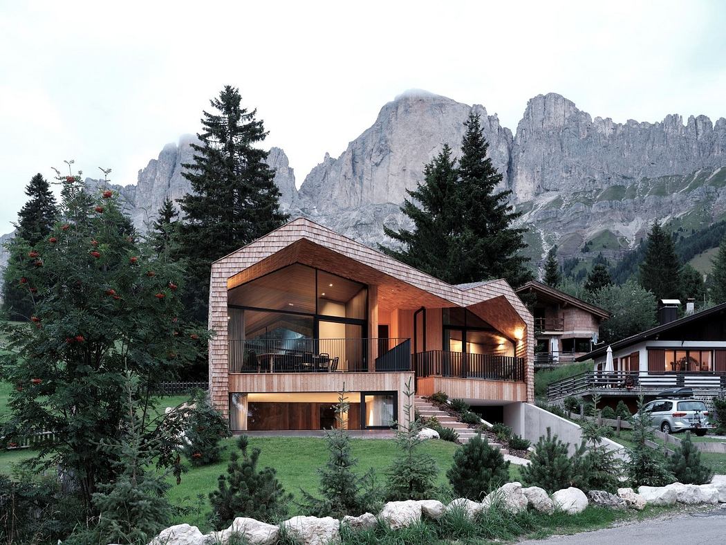 Modern cabin with large windows set against a rugged mountain backdrop.