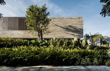 Modern concrete building with lush greenery in the foreground.