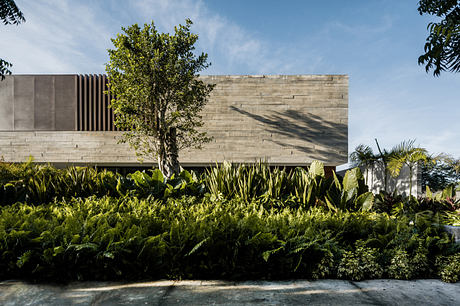 Modern concrete building with lush greenery in the foreground.