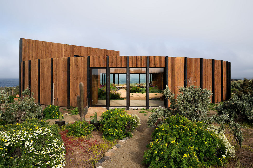 Modern wooden house with large glass doors surrounded by native plants.