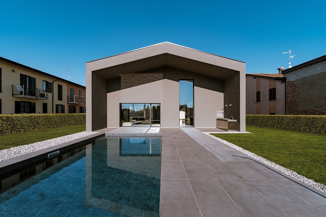 Modern minimalist house facade with large open portal and reflecting pool.