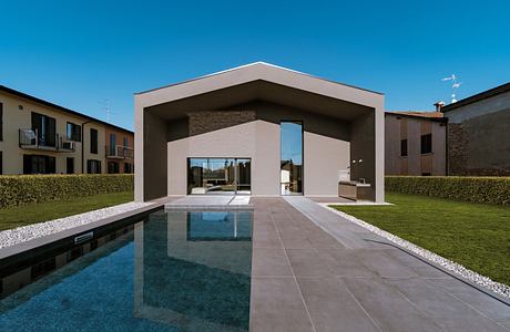 Modern minimalist house facade with large open portal and reflecting pool.