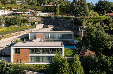 Modern terraced house with large windows, surrounded by greenery.