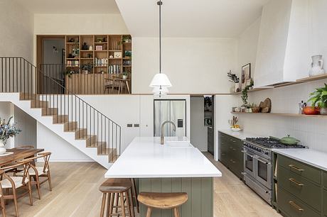 Modern kitchen with island, open shelving, and staircase.