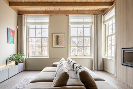 Bright modern living room with large windows, wooden ceiling, and beige sofa.