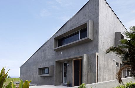 Modern concrete house with geometric design and ocean view.