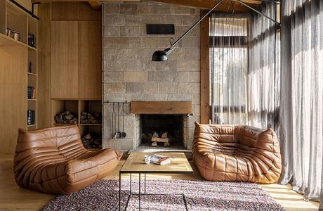 Cozy living room with fireplace, plush chairs, and wooden bookshelf.