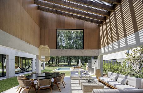 Modern living room with large windows, wooden ceiling, and minimalist furniture overlooking a pool