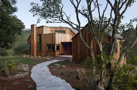 Modern wooden house with angular design amidst forest setting.