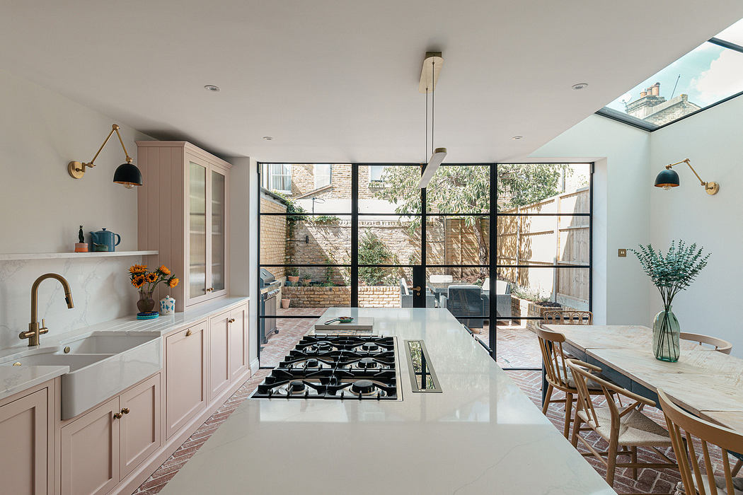 Modern kitchen with pink cabinets, large island, and glass wall overlooking a courtyard.