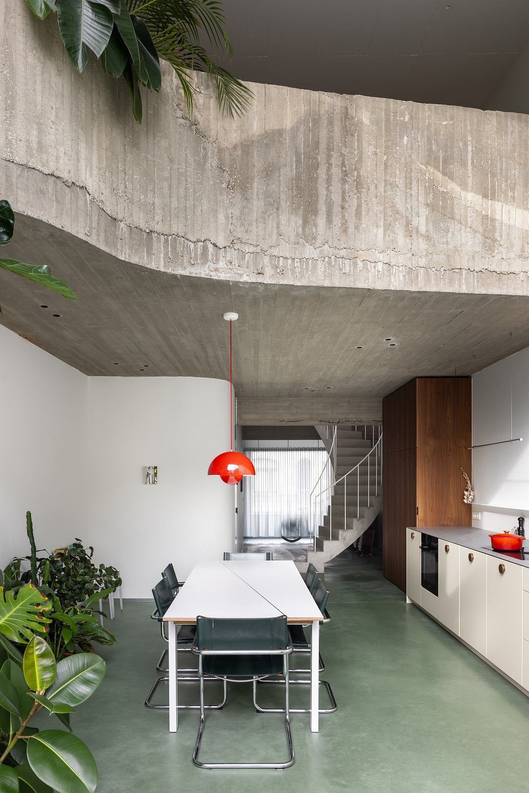 Modern interior with exposed concrete ceiling, minimalist furniture, and greenery.
