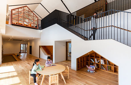 Modern home interior with geometric staircase and mezzanine, people interacting.