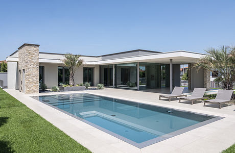 Modern single-story house with pool and lounge chairs.