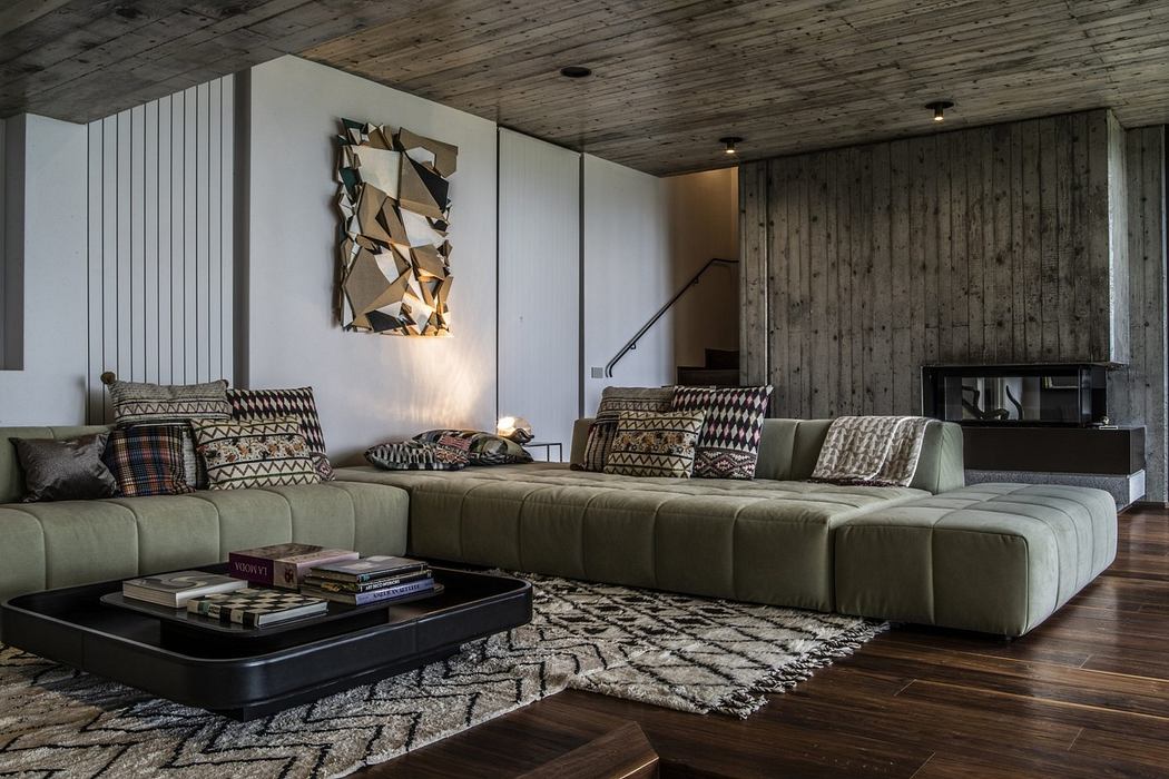 Rustic modern living room with wooden walls and large sectional sofa.