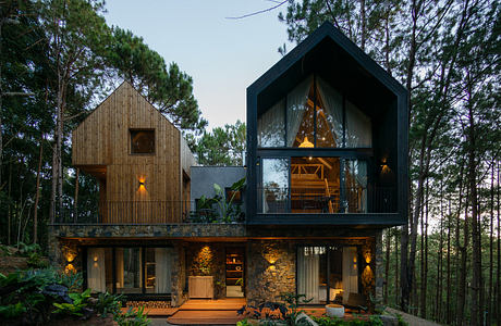 Modern two-story house with mixed-material facade surrounded by trees at dusk.