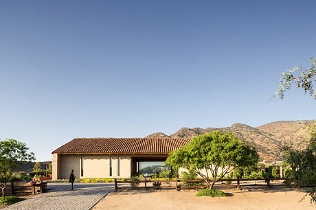 Modern single-story building with large windows, set against mountains.