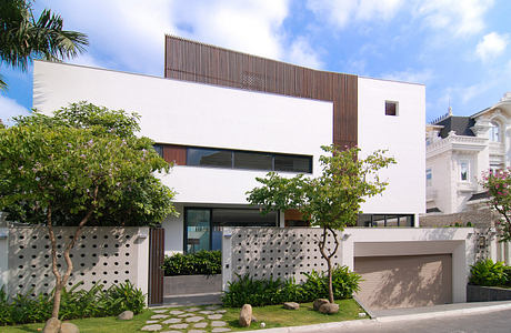 Modern two-story house with white facade and wooden accents.