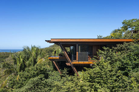 Modern home with large overhang nestled in a lush green forest.