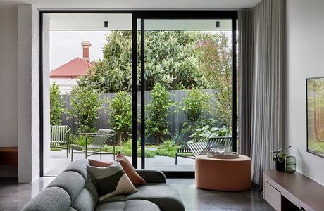 Modern living room with floor-to-ceiling windows overlooking a garden.