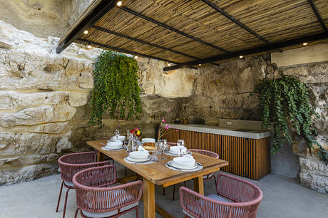 Rustic outdoor dining area with stone walls and wooden furniture.