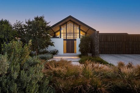 Modern house at twilight with illuminated windows and landscaped garden.