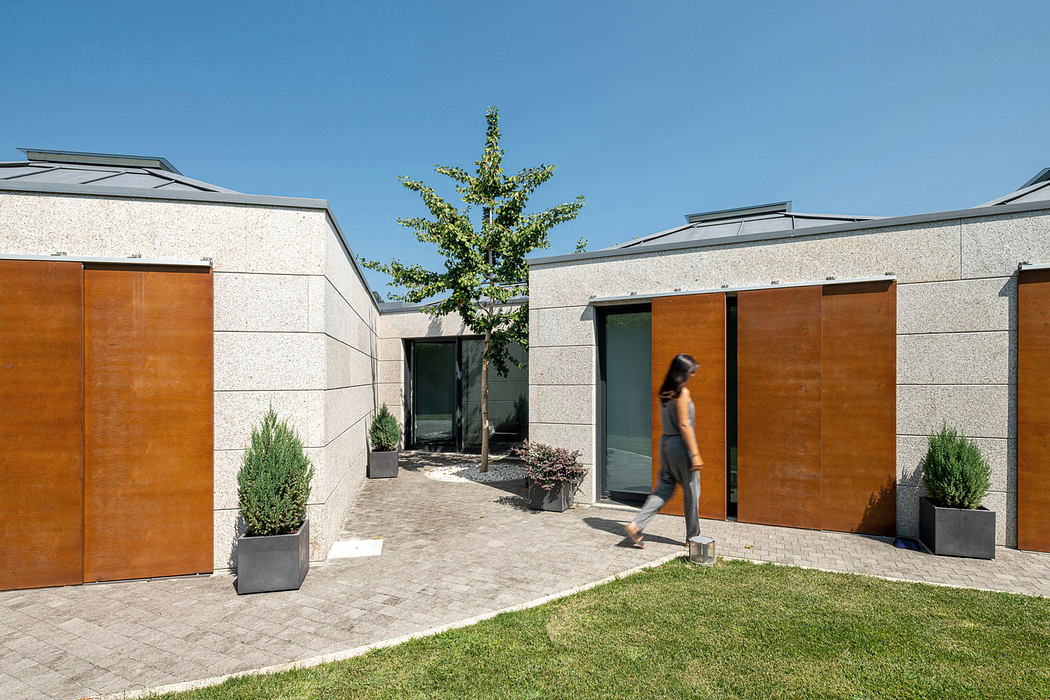 Modern courtyard with geometric design, green lawn, and a person walking.