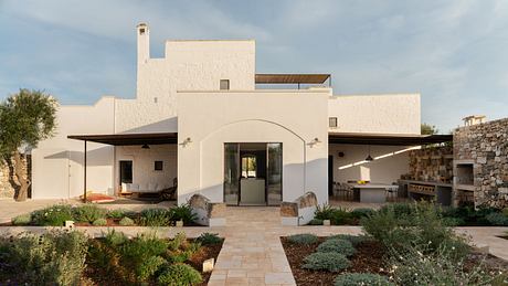 A modern white villa with archway entrance and landscaped garden.