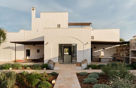 A modern white villa with archway entrance and landscaped garden.